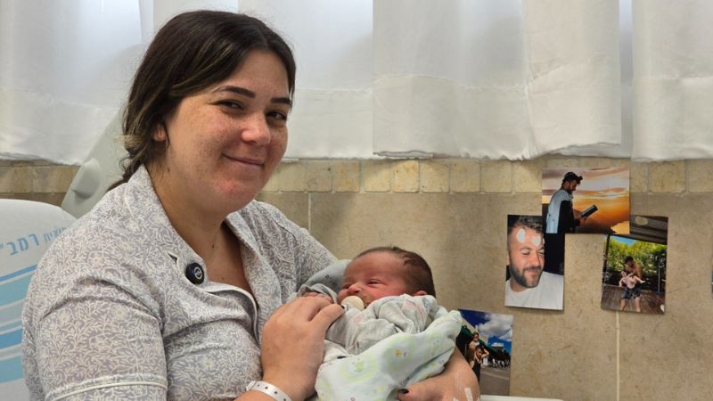 שובל קוסטנקו–צרפתי ובנה שנולד אתמול ברמב"ם. על הקיר, תמונותיו של אחיה, אופיר צרפתי ז"ל | צילום: הקריה הרפואית רמב"ם.