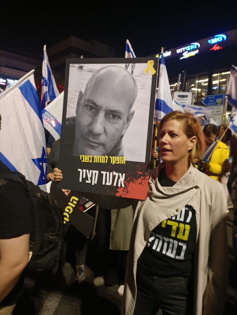 כרמית פלטי קציר עם תמונתו של אלעד קציר, אחיה, שנרצח בשבי חמאס | צילום: מחאת העם חיפה