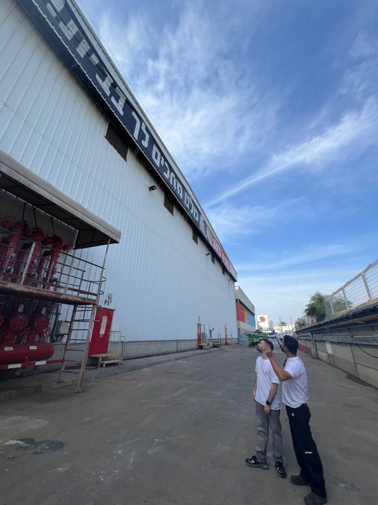 מתן אנגרסט מתחת לשלט במפעל טמבור בעכו | צילום: טמבור