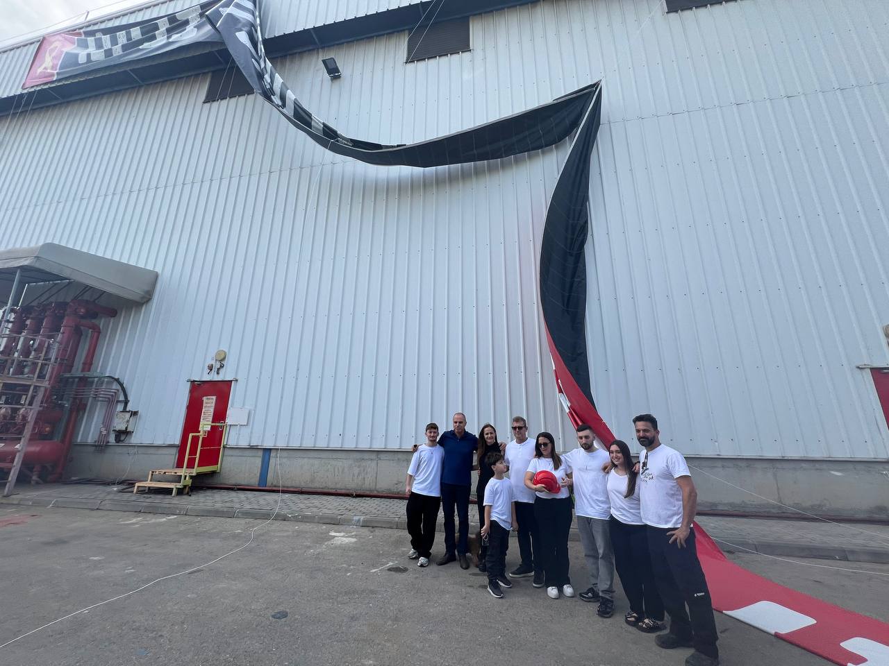 מתן אנגרסט ובני משפחתו מתחת לשלט במפעל טמבור בעכו | צילום: טמבור