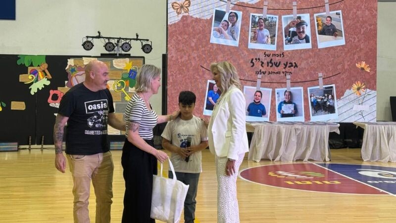 המנהלת טלי אינדיבו ותלמיד מעניקים את ספר וחולצת המחזור להוריו של גבע שליו ז